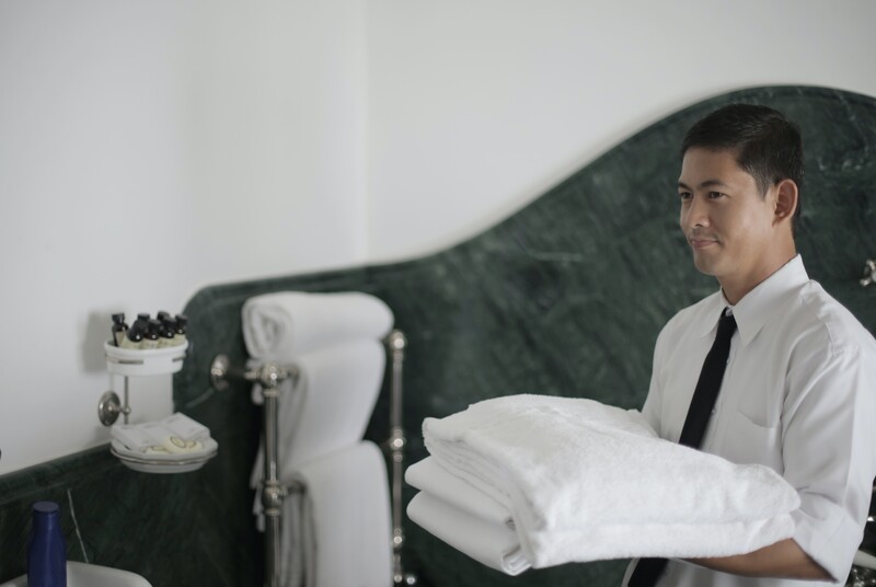 Funcionário uniformizado segurando toalhas brancas