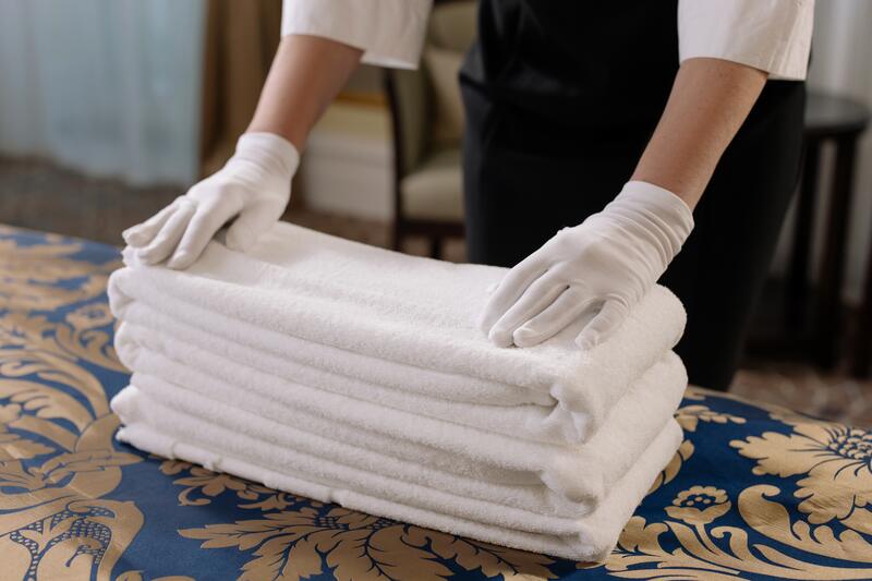 Funcionário dobrando toalhas brancas do hotel em que trabalha 